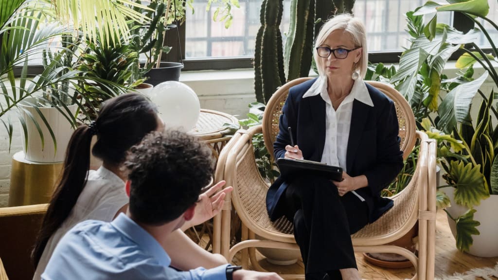 A woman sitting in a chair and talking to a group of people.